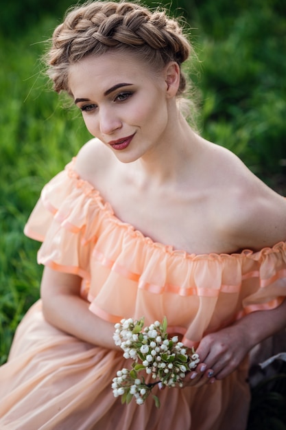 Menina com cabelo loiro em um vestido leve no jardim florido. conceito de moda feminina primavera.