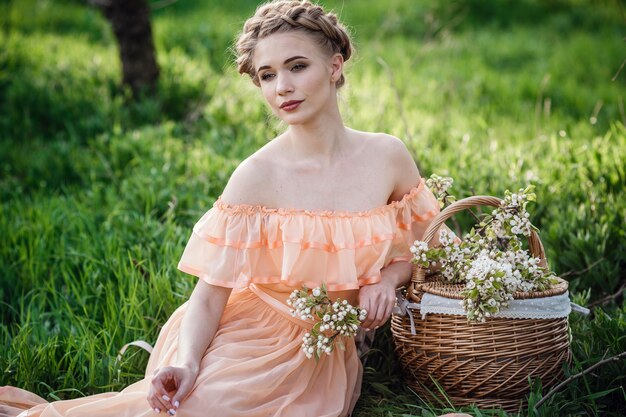 Menina com cabelo loiro em um vestido leve no jardim florido. conceito de moda feminina primavera.