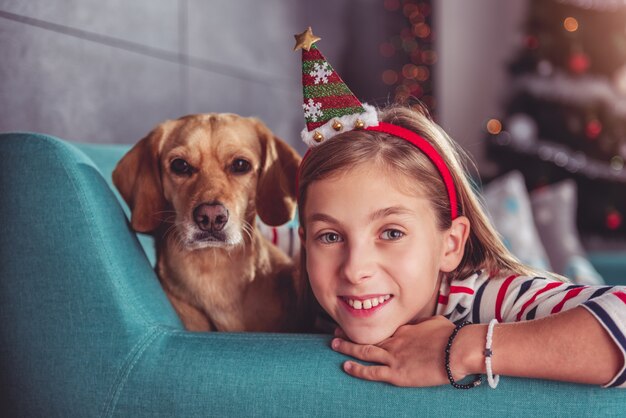 Menina com cachorro amarelo posando no sofá