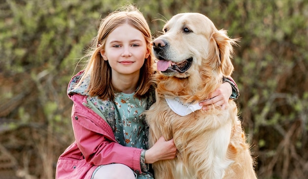 Menina com cachorro golden retriever ao ar livre no parque primavera, criança bonita com cachorro de estimação labrad