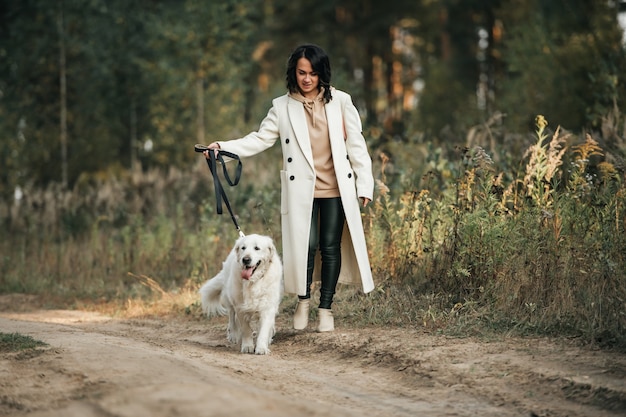 Menina com cachorro golden retriever branco no caminho da floresta