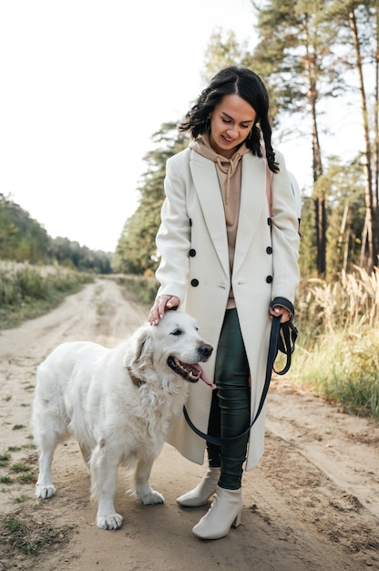 Menina com cachorro golden retriever branco no caminho da floresta