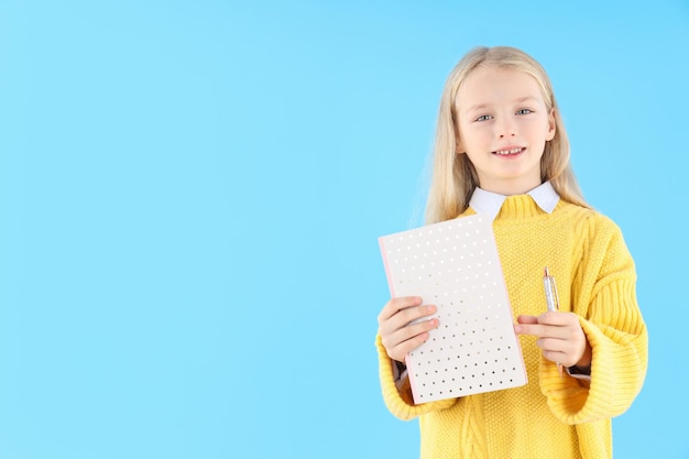 Menina com caderno e caneta sobre fundo azul