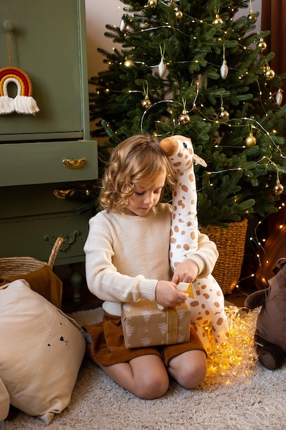 Foto menina com caixas de presente e árvore de natal em fundo