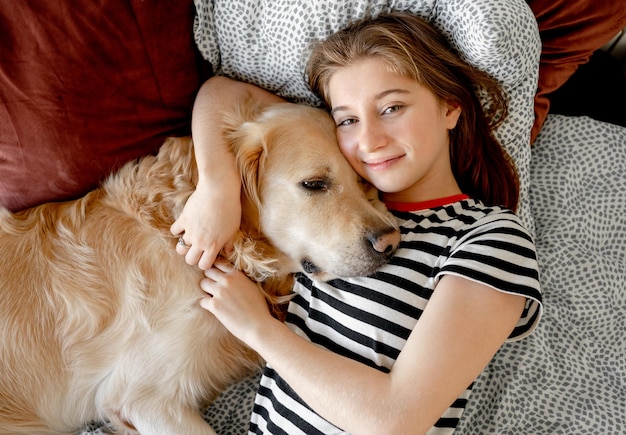 Menina com cão retriever dourado na cama