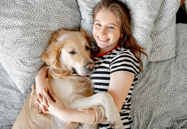 Menina com cão retriever dourado na cama