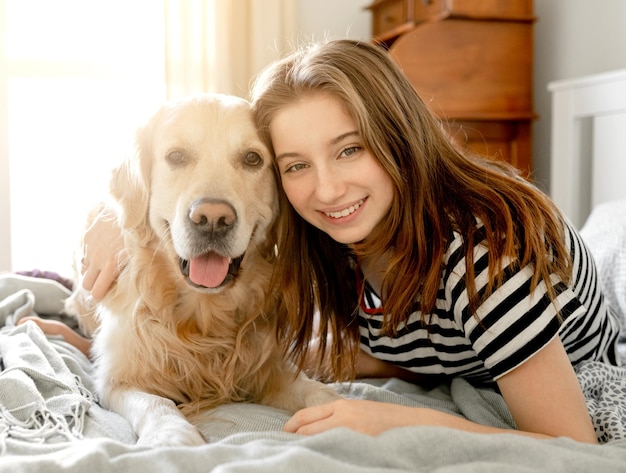 Menina com cão retriever dourado na cama