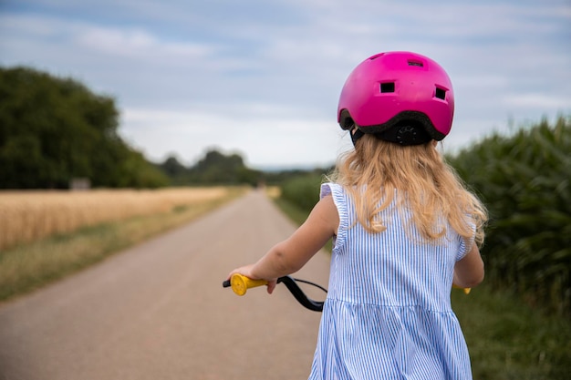 Menina com capacete anda de bicicleta em um campo