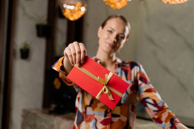 Menina com cartão-presente. Mulher segurando o cupom certificado vermelho - presente para férias.