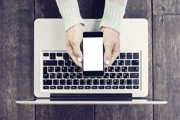 Menina com celular e laptop em branco