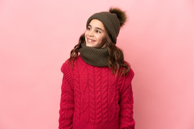 Menina com chapéu de inverno isolada na parede rosa tendo uma ideia enquanto olha para cima