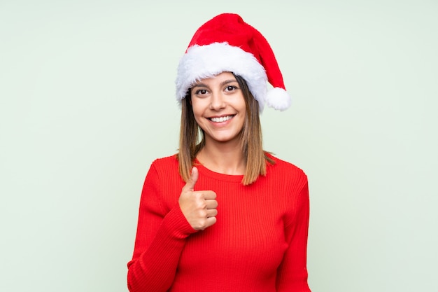 Menina com chapéu de Natal isolado verde dando um polegar para cima gesto