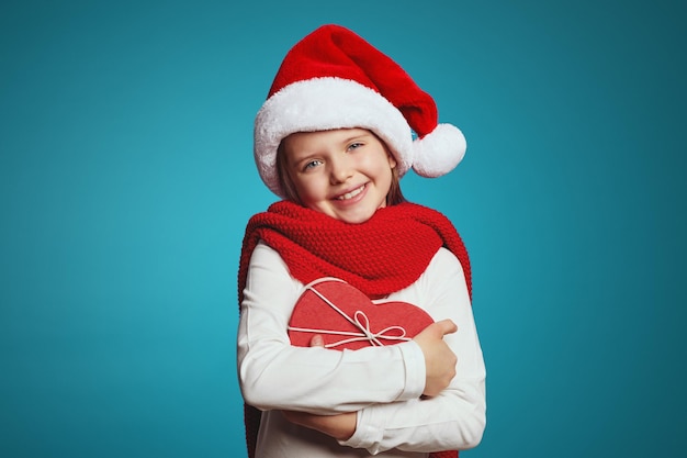 Menina com chapéu de Natal, lenço vermelho e caixa de presente em forma de