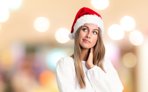 Menina com chapéu de Natal, pensando uma idéia sobre parede fora de foco