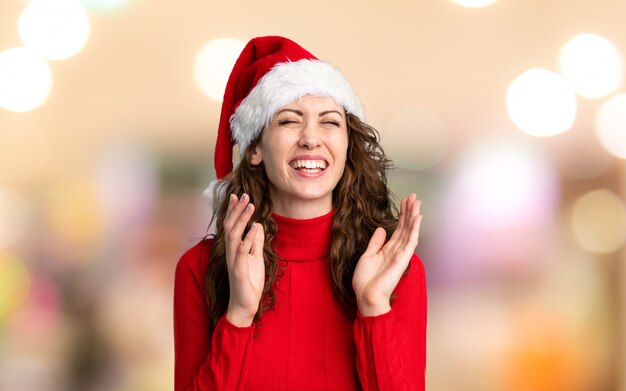 Menina com chapéu de Natal rindo sobre parede fora de foco