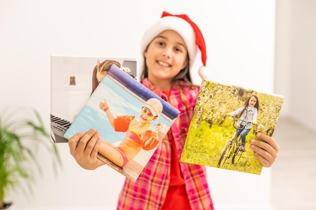 Menina com chapéu de papai noel sorrindo e segurando a tela de fotos na mão. conceito de natal. copie o espaço.