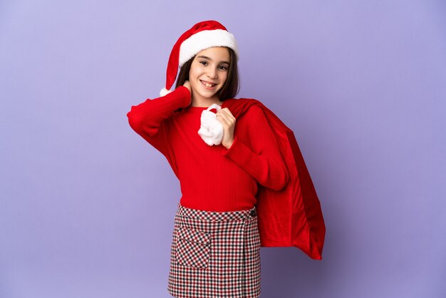 Menina com chapéu e saco de Natal isolado no fundo roxo rindo