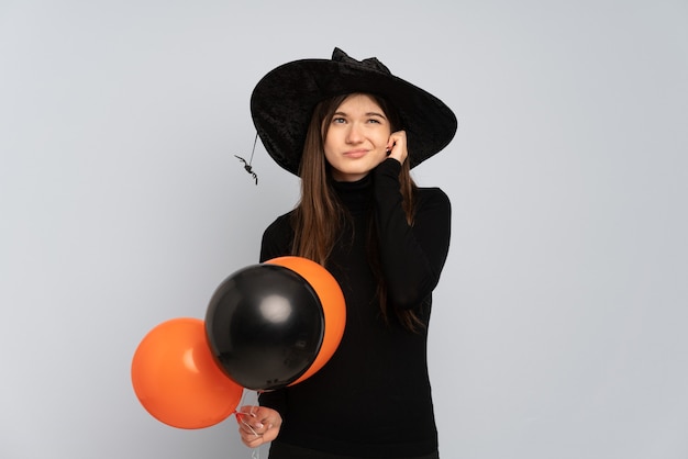 Menina com chapéu preto e vestido preto segurando balões