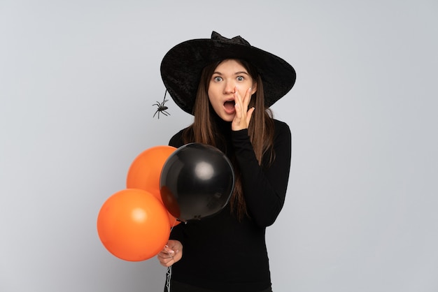 Menina com chapéu preto e vestido preto segurando balões