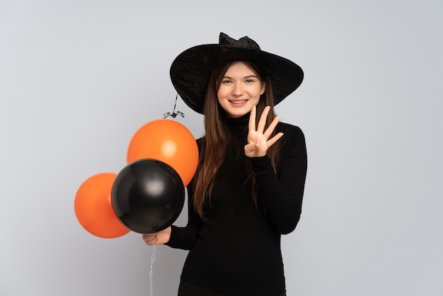 Menina com chapéu preto e vestido preto segurando balões