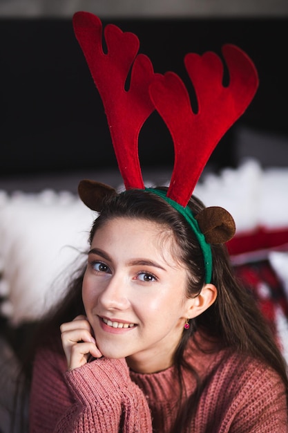 Menina com chifres de veado no fundo da árvore de Natal.