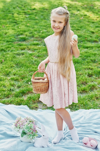 menina com coelho e ovos para a páscoa no parque na grama verde