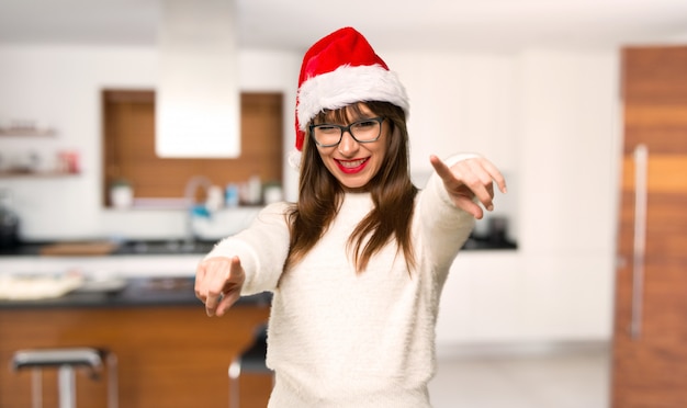 Menina com comemorando as férias de Natal aponta o dedo para você enquanto sorrindo em casa