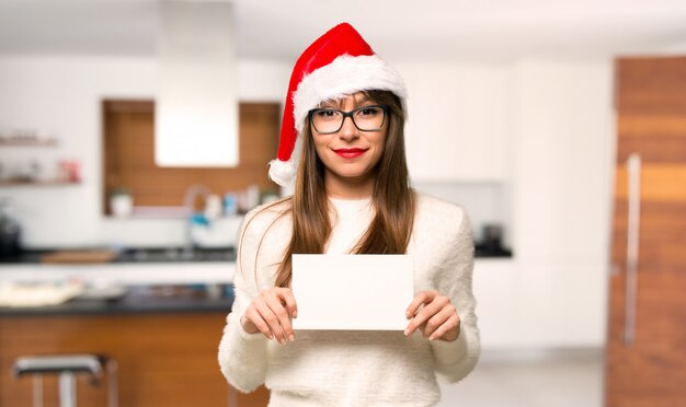 Foto menina com comemorando as férias de natal, segurando um cartaz branco vazio