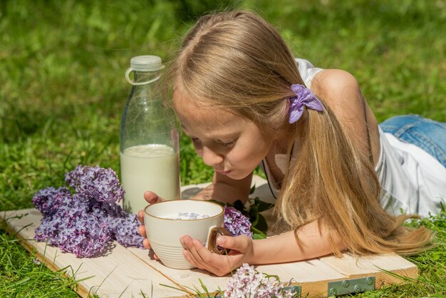 Menina com copo de leite na natureza