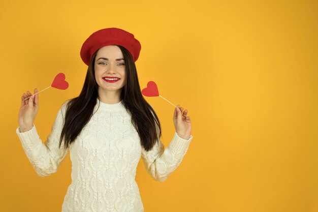 Menina com coração em um espaço de parede amarelo liso monocromático para texto