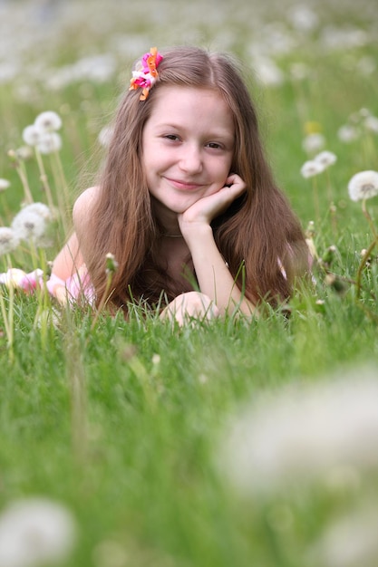 Menina com dente de leão e prado verde ao fundo