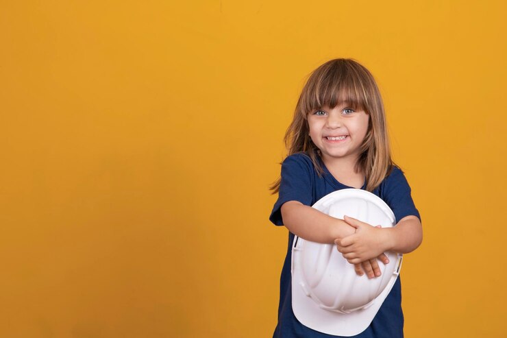 Foto menina com ferramentas de construção menina com capacete de segurança e proteção infantil menina bonitinha que sonha em ser um arquiteto sorrindo com espaço livre para texto