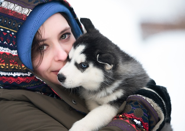 Menina com filhote de cachorro husky no fundo do inverno