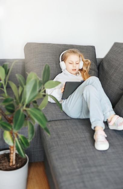 Menina com fones de ouvido e tablet em casa