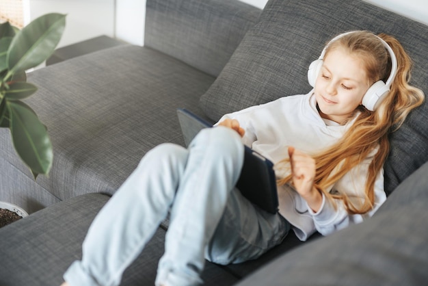 Menina com fones de ouvido e tablet em casa