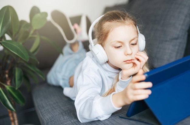 Menina com fones de ouvido e tablet em casa