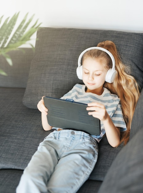 Menina com fones de ouvido e tablet em casa