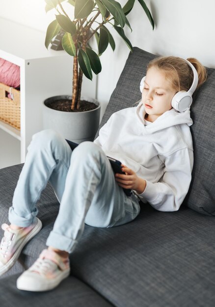 Menina com fones de ouvido e tablet em casa