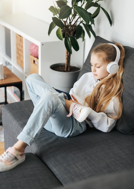 Menina com fones de ouvido e tablet em casa