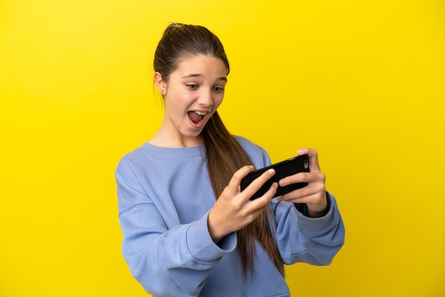 Menina com fundo amarelo isolado brincando com o celular