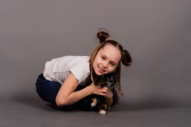 Menina com gatinho preto, isolado nas costas cinza