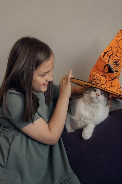 Menina com gato de chapéu laranja, conceito de halloween