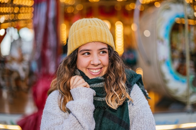 Menina com gorro de lã amarela e lenço em uma feira de Natal