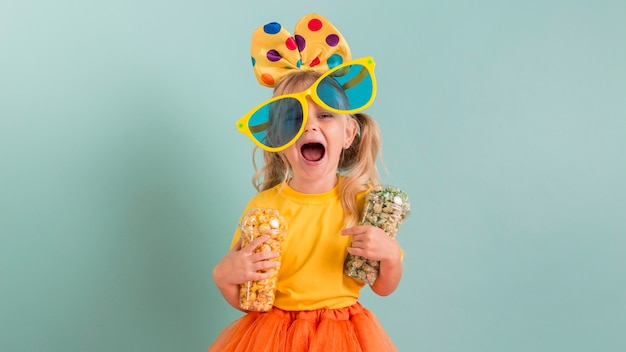 Foto menina com grandes óculos escuros e doces nas mãos