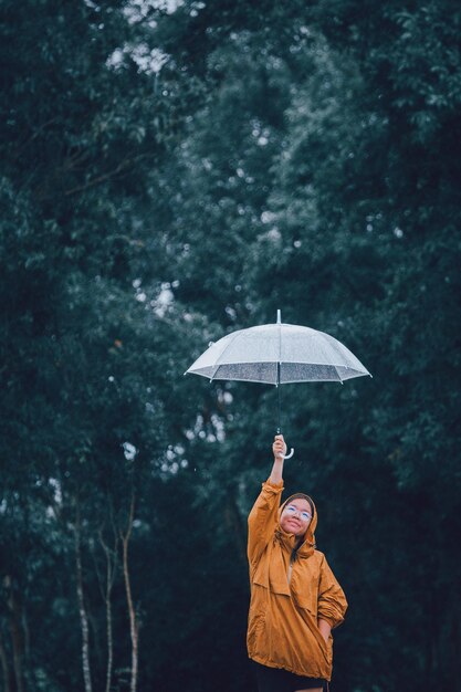 Menina com guarda-chuva de pé na floresta