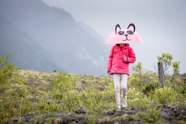 Menina com guarda-chuva panda caminhando na montanha