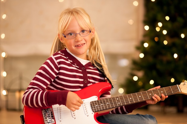 Menina, com, guitarra, frente, árvore natal