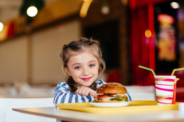 Menina com hambúrguer e refrigerante