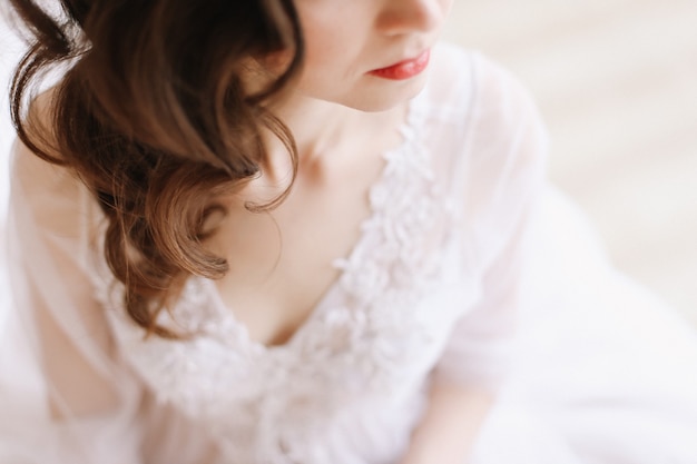 Menina com lábios vermelhos no perfil. Retrato do close-up de uma jovem. Detalhes do casamento. Manhã da noiva.