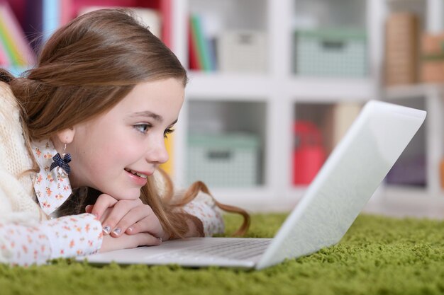 Menina com laptop deitado no tapete